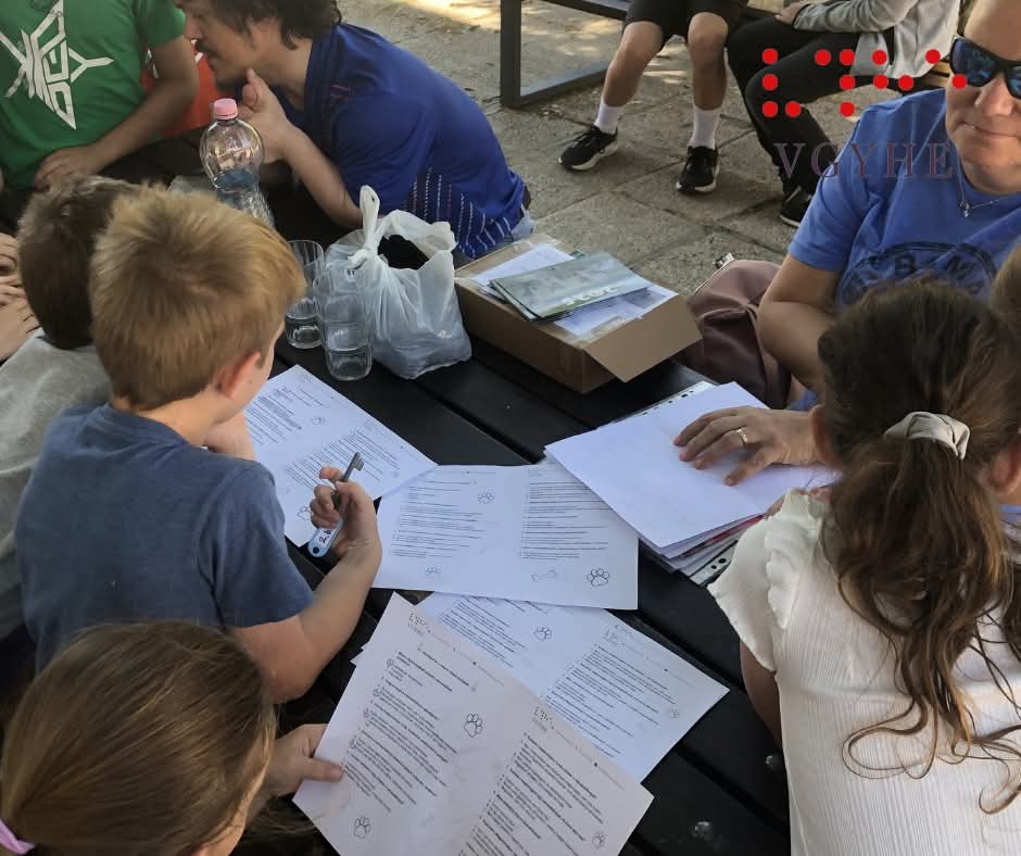 A képen diákok egy csoportja látszik hátulról, ahogy épp elmélyülten töltögetik a vakvezetőkutyás kvízkérdéseket tartalmazó papírlapot.