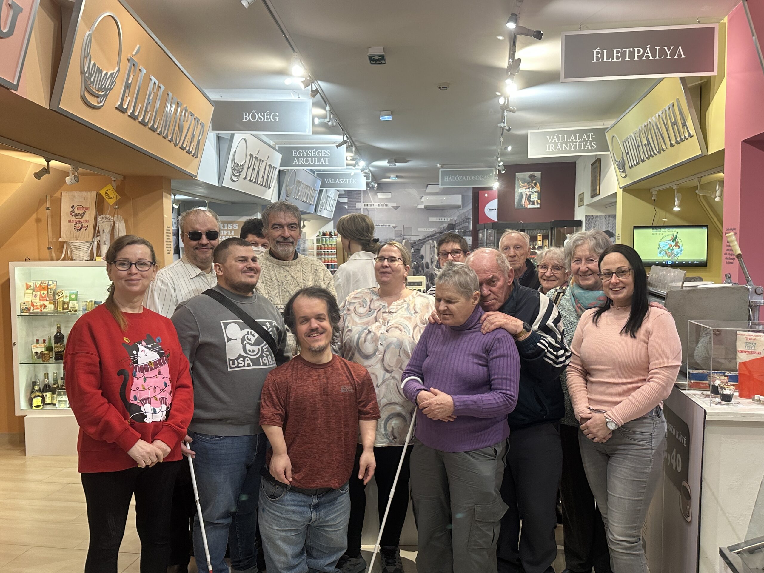 A képen a résztvevőkről készített csoportkép látható, háttérben a kiállítás elemeivel.