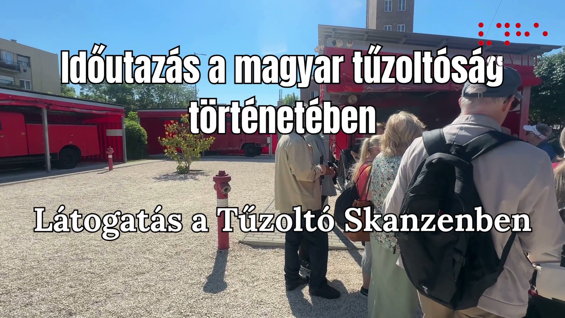 Látássérültek és kisérőik , a háttérben régi tűzoltóautók. A képen felirat: „Időutazás a magyar tűzoltóság történetében – látogatás a Tűzoltó Skanzenben”